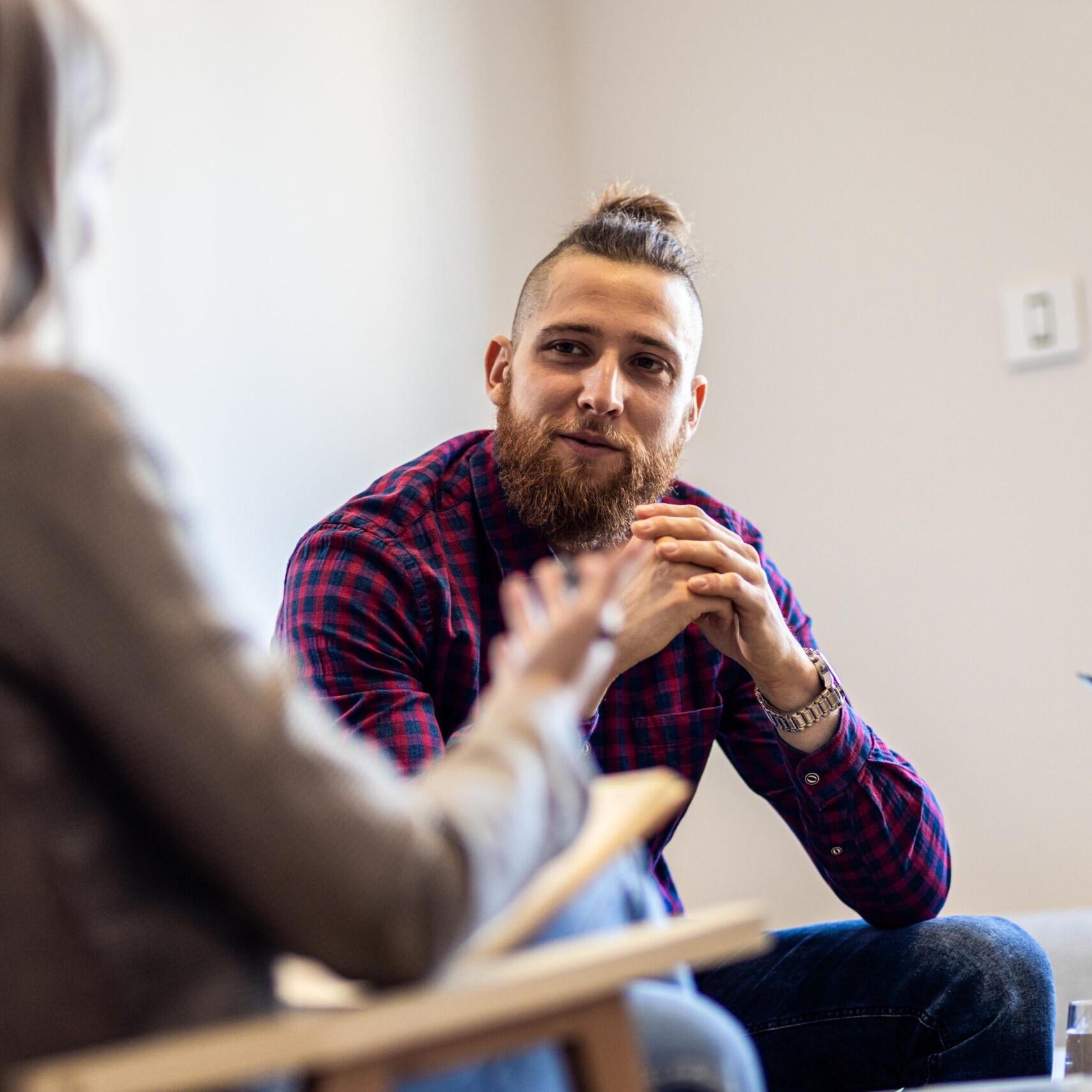Female psychologist talking to young man during session.