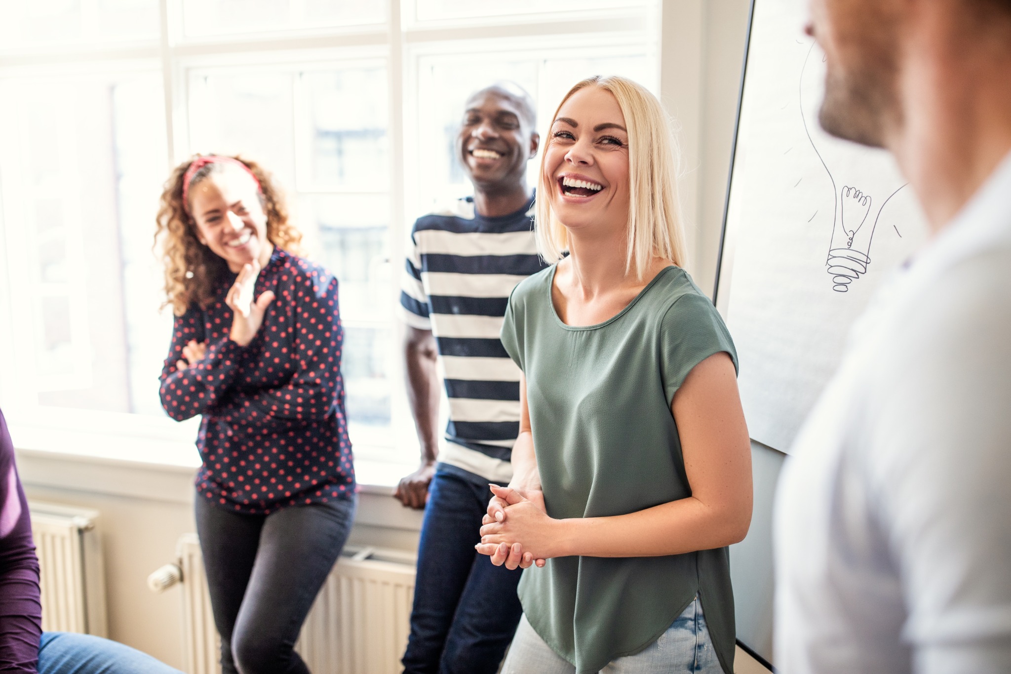 Lächelnde Mitarbeitende im persönlichen Austausch bei einem moderierten Teamformat